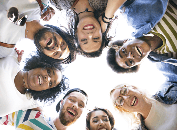 Circle of people leaning down to smile into the camera